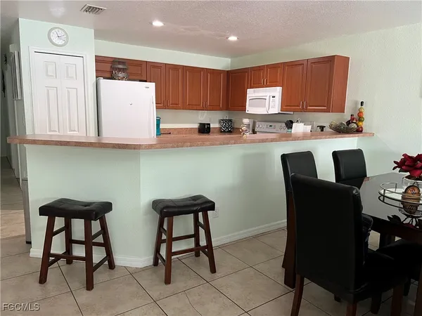 a kitchen with stainless steel appliances granite countertop a table chairs refrigerator and sink