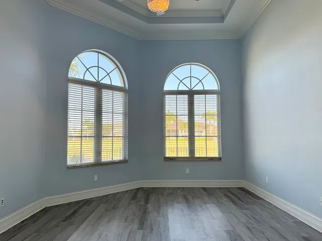 an empty room with wooden floor windows and a closet