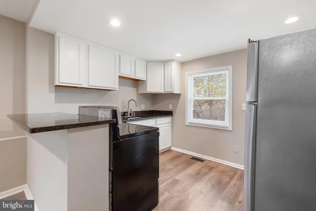 a kitchen with granite countertop a refrigerator stove top oven and sink