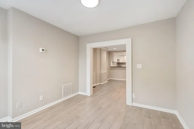 a view of a hallway with wooden floor and a bathroom