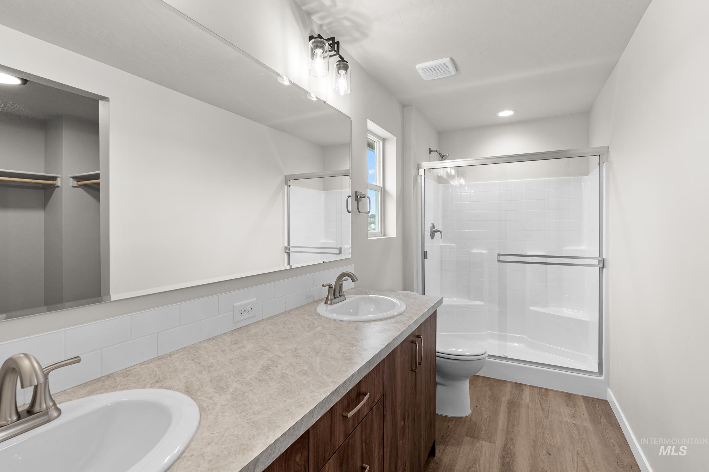 503 Hamlow Avenue Middleton, ID 83644 - Photo 19 of 21 Bathroom featuring a shower stall, double vanity, light wood-type flooring, and a walk in closet