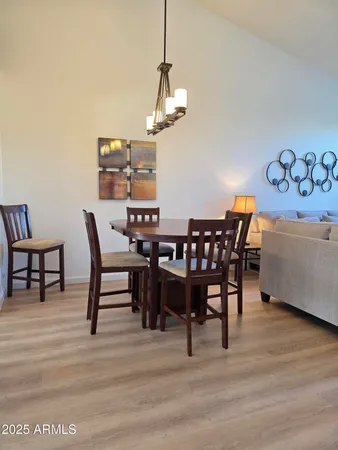 a kitchen with stainless steel appliances granite countertop wooden cabinets a sink a stove a dining table and chairs