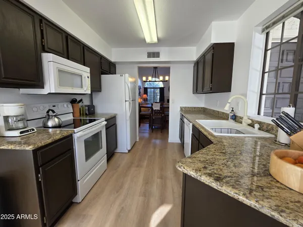 a kitchen with stainless steel appliances granite countertop a refrigerator a stove and a sink