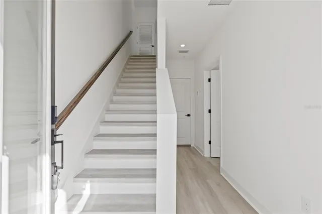 a view of staircase with wooden floor and white walls