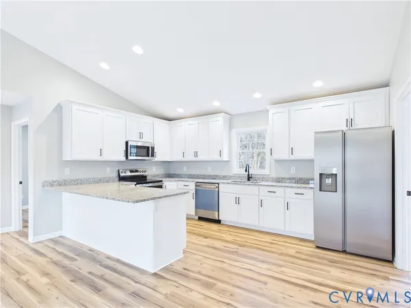 a kitchen with stainless steel appliances granite countertop a stove a refrigerator a sink a oven and white cabinets with wooden floor