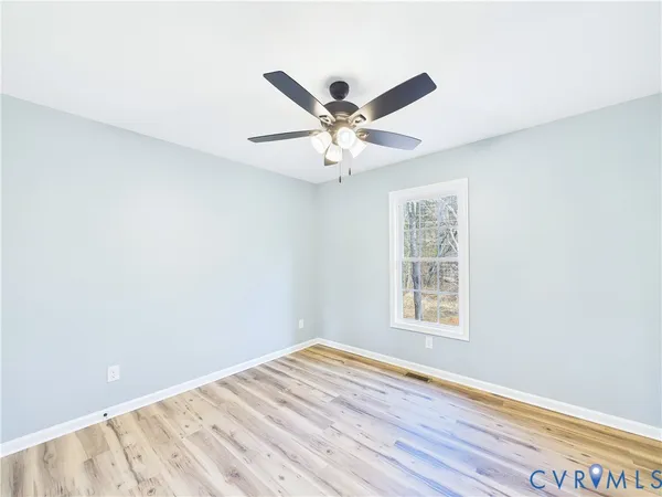 a view of an empty room with window and wooden floor