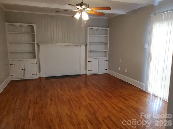an empty room with wooden floor closet and windows