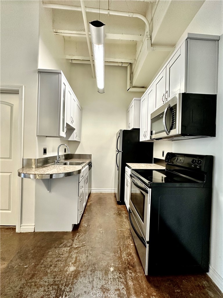 312 West 5th Street, Unit 604 Los Angeles, CA 90013 - Photo 3 of 13 a kitchen with stainless steel appliances kitchen island granite countertop a stove top oven a sink a microwave and a refrigerator