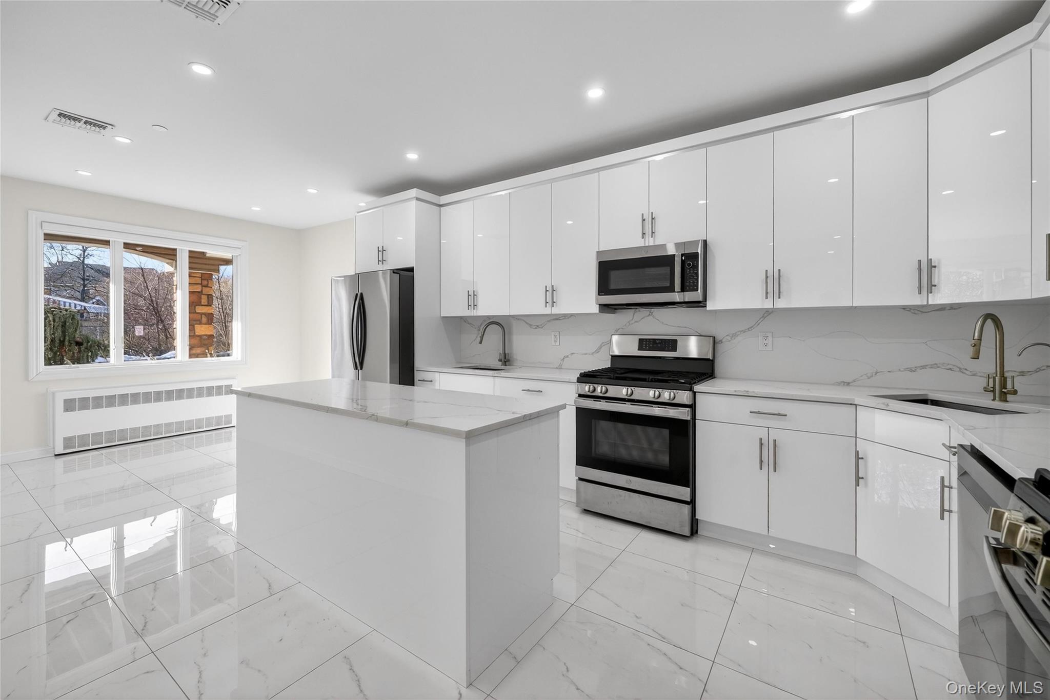 Kitchen with stainless steel appliances, a center island, white cabinetry, radiator heating unit, and light stone countertops