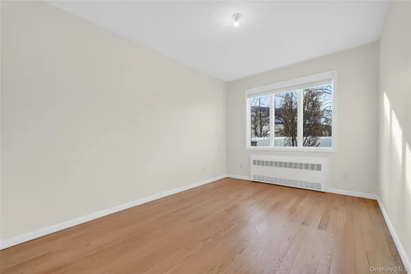 a view of an empty room with a window and wooden floor