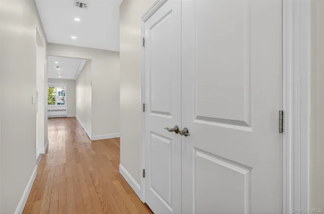 a view of an empty room with wooden floor and closet