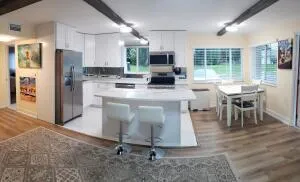 a kitchen with kitchen island granite countertop a table chairs sink and refrigerator