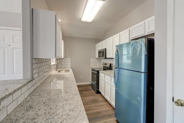 a kitchen with stainless steel appliances granite countertop a refrigerator a stove and a sink