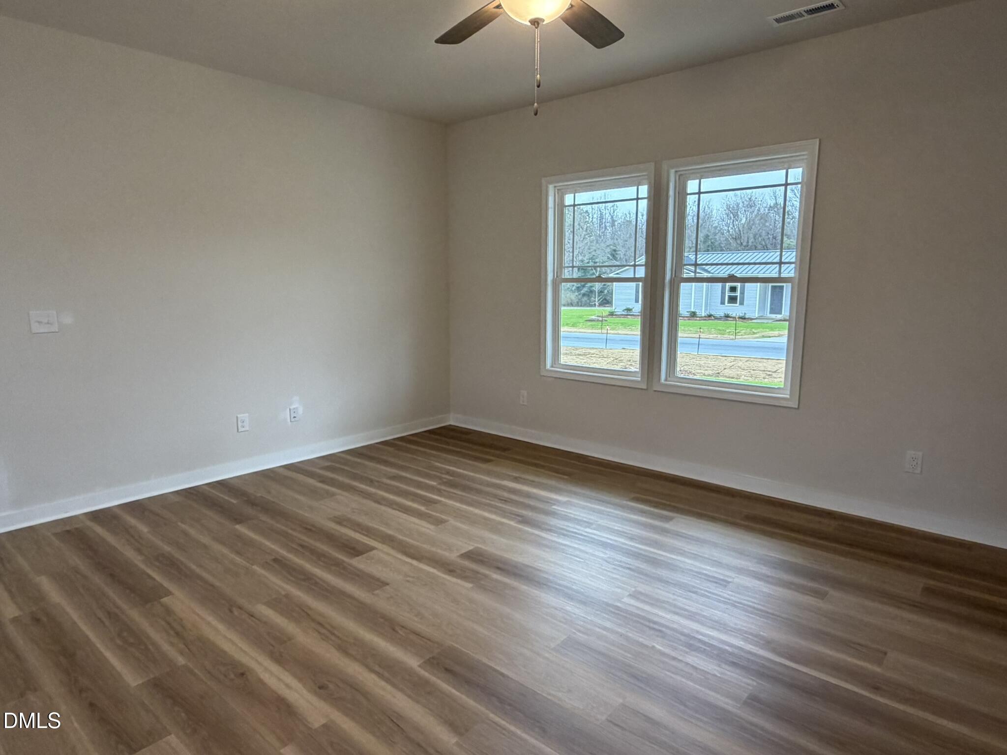 219 Jacobs Ridge Drive Four Oaks, NC 27524 - Photo 6 of 19 an empty room with wooden floor chandelier fan and windows