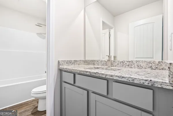 a bathroom with a granite countertop toilet a sink and a bathtub