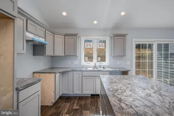 a open kitchen with kitchen island granite countertop a sink stove and cabinets