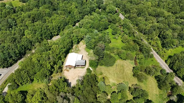an aerial view of residential house with outdoor space and trees all around