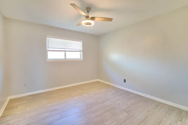 an empty room with a window and a fan