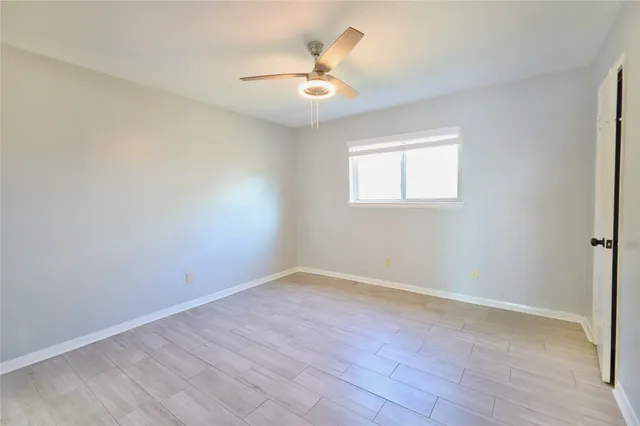 an empty room with a window and a fan
