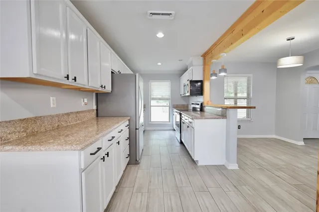 a kitchen with stainless steel appliances granite countertop a stove top oven a sink dishwasher and a refrigerator with wooden floor