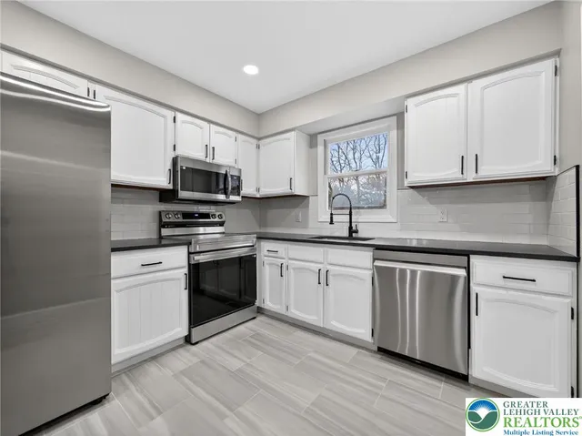 a kitchen with granite countertop white cabinets and stainless steel appliances
