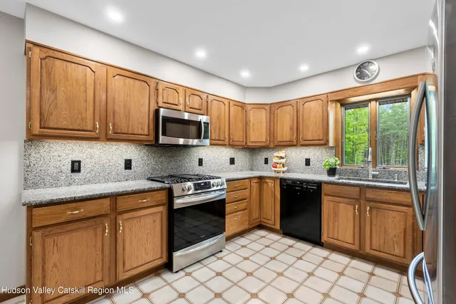 a kitchen with stainless steel appliances granite countertop a stove top oven a sink dishwasher a dining table and chairs with wooden cabinets