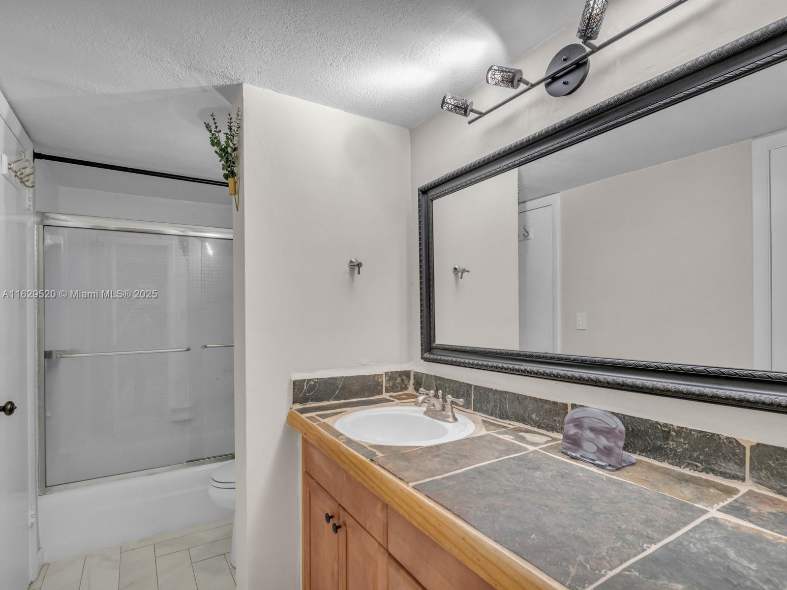7403 Southwest 82nd Street, Unit 201N Miami, FL 33143 - Photo 22 of 43 a bathroom with a granite countertop sink and a mirror