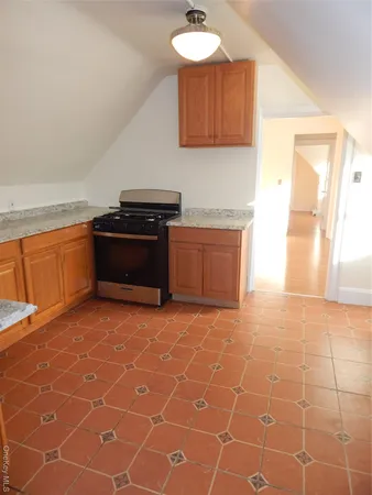 a kitchen with granite countertop a stove a sink a counter top space and cabinets