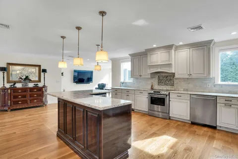 a kitchen with stainless steel appliances granite countertop a sink a stove and a wooden floor