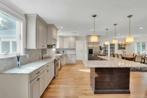 a large kitchen with kitchen island granite countertop a sink a counter top space and stainless steel appliances