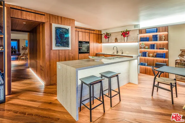 a kitchen with stainless steel appliances a dining table chairs and wooden floor