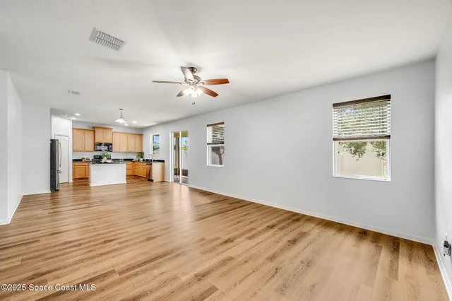 a view of an empty room with kitchen view and a window