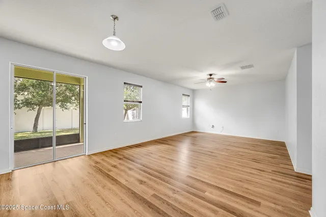 a view of empty room with wooden floor and ceiling fan