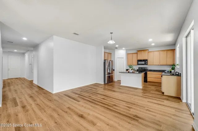 a view of kitchen with kitchen island a sink wooden floor and a refrigerator