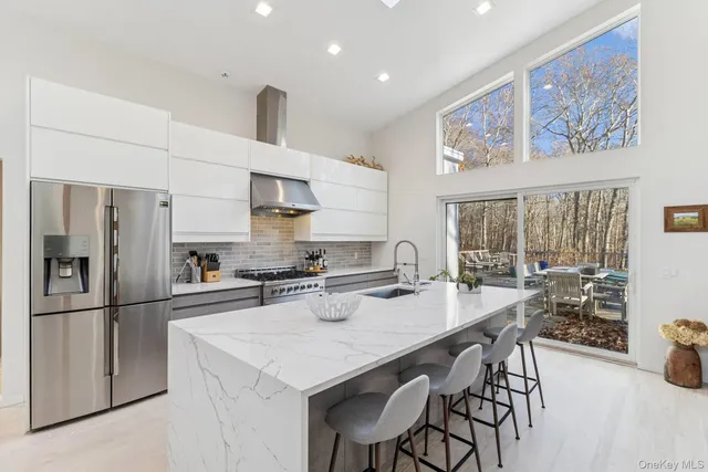 a kitchen with stainless steel appliances a dining table chairs and refrigerator