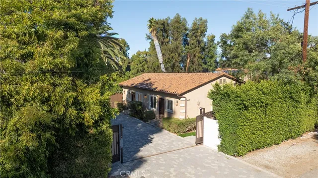 a view of a house with a small yard plants and large tree