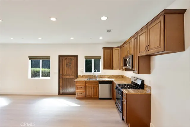 a living room with stainless steel appliances granite countertop a sink a stove and a refrigerator