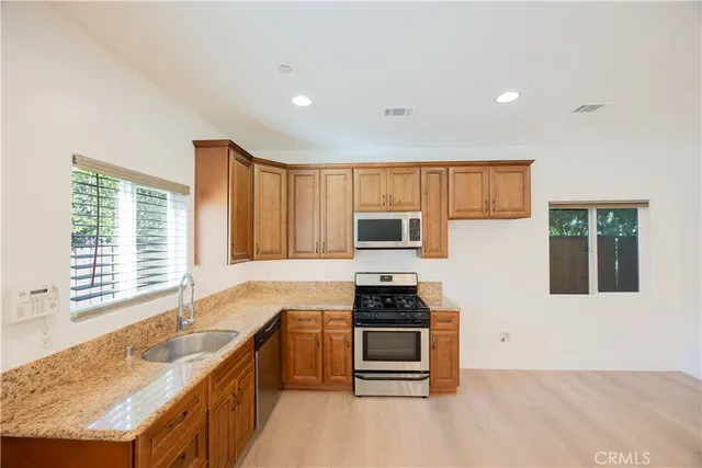 a kitchen with stainless steel appliances granite countertop a stove a sink and a microwave