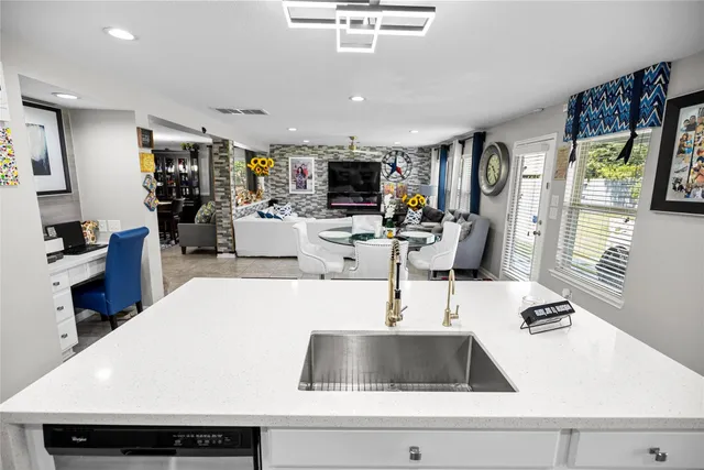 a kitchen with a sink a counter top space and living room view