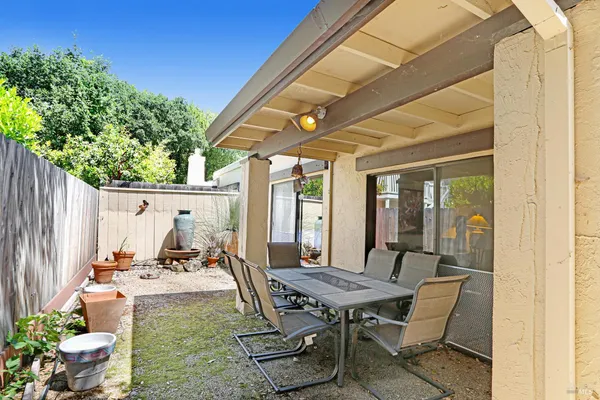 a view of a backyard with table and chairs potted plants and floor to ceiling window
