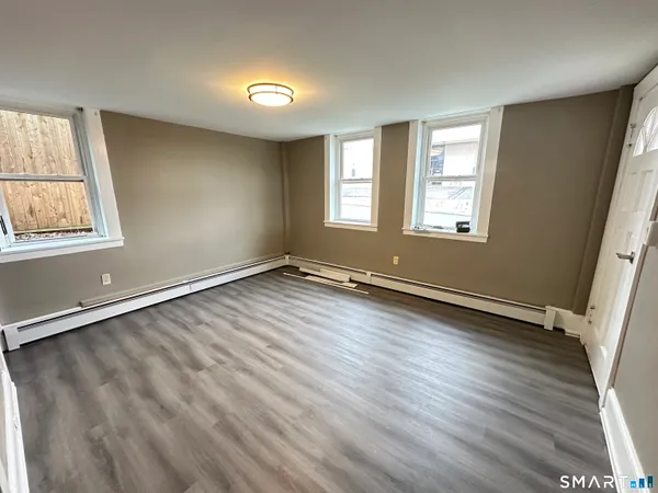 an empty room with wooden floor and windows