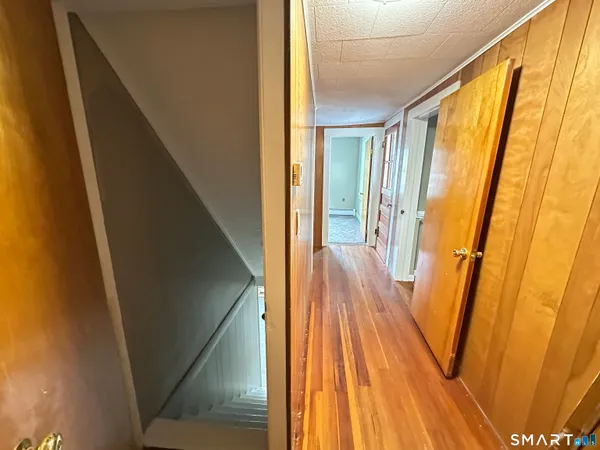 a view of a hallway with wooden floor and staircase