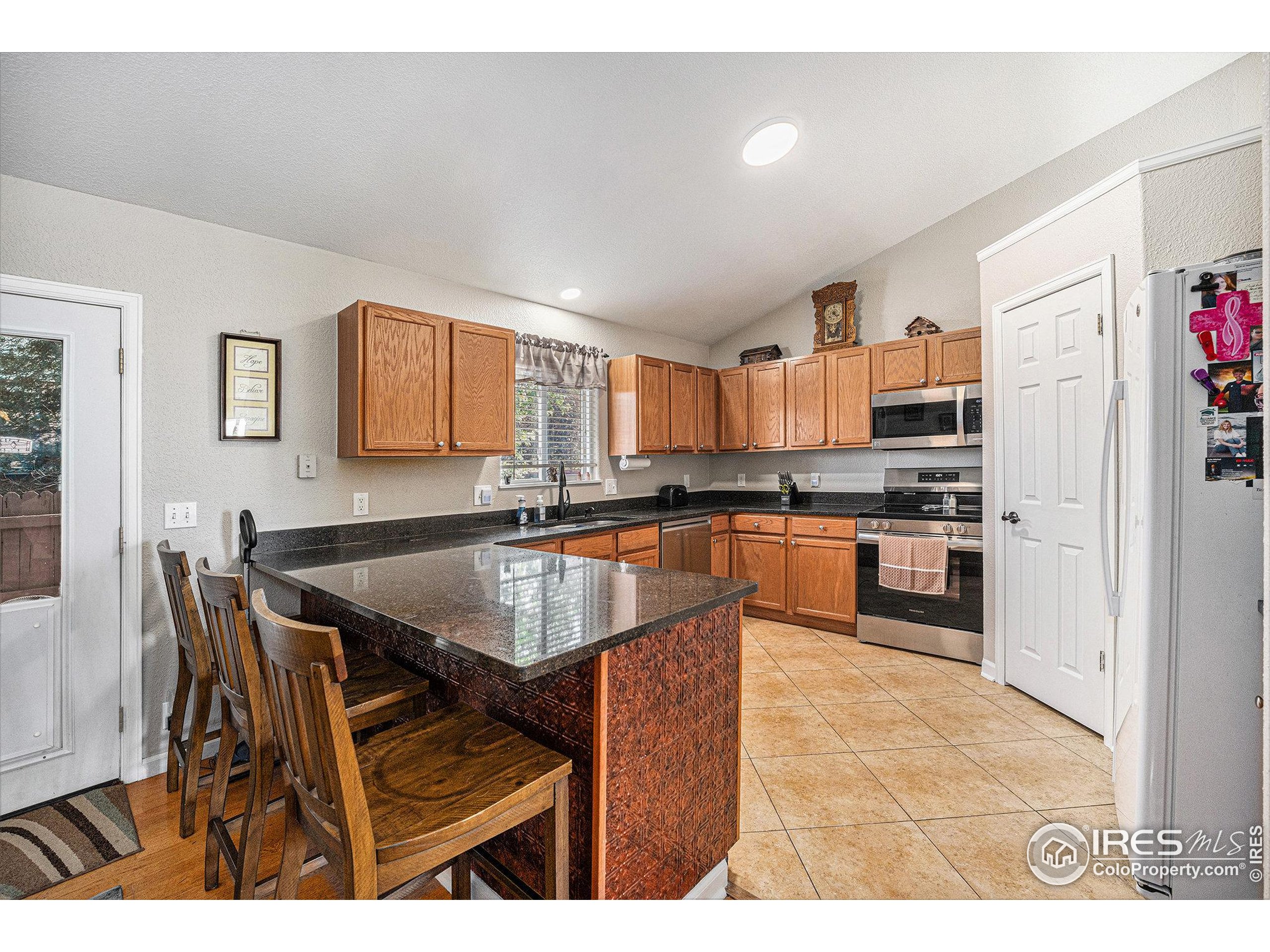 1030 South Fulton Avenue Fort Lupton, CO 80621 - Photo 6 of 26 a kitchen with stainless steel appliances kitchen island granite countertop a sink a stove a dining table and chairs