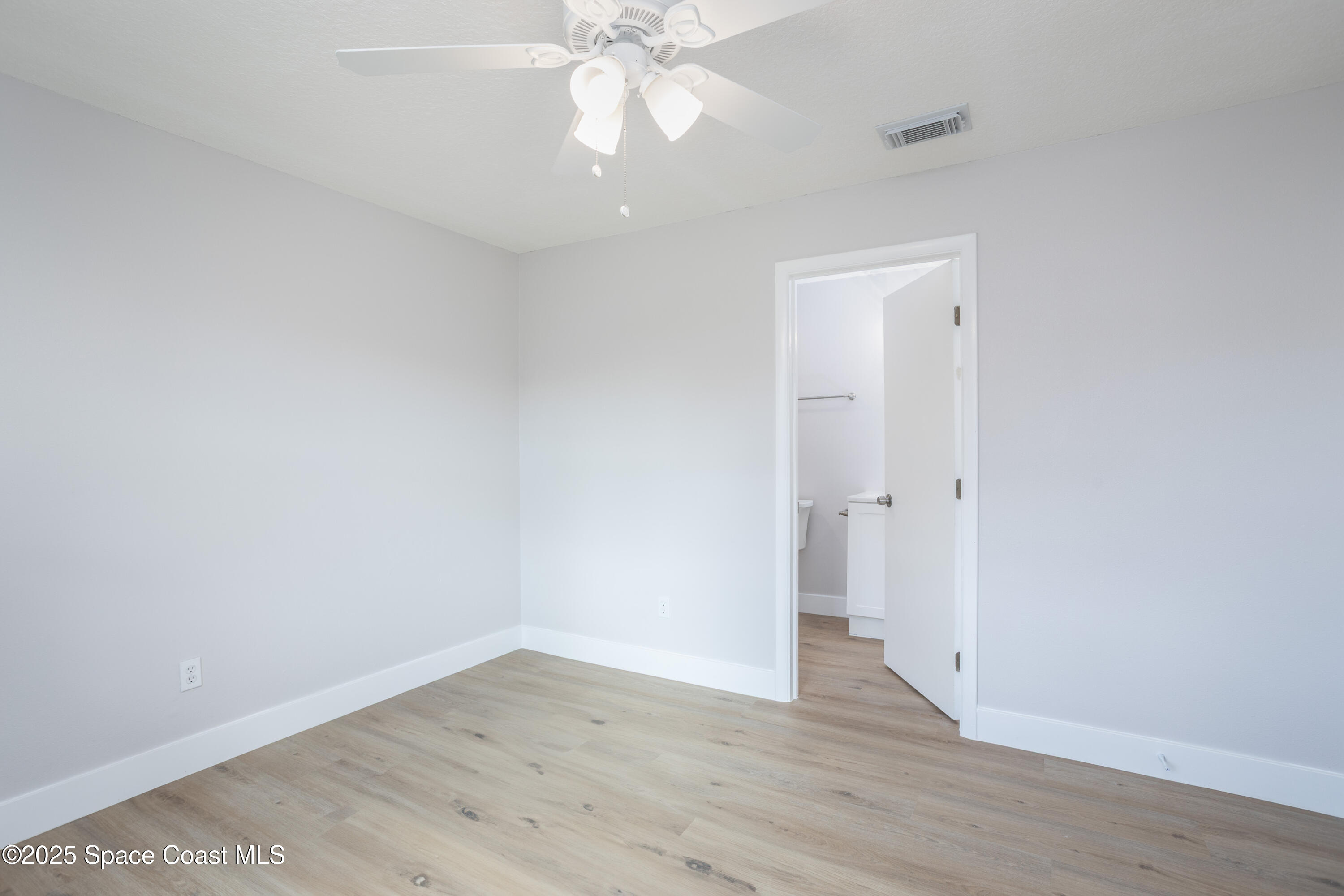 5446 Jamaica Road Cocoa, FL 32927 - Photo 12 of 21 a view of an empty room with wooden floor and a ceiling fan