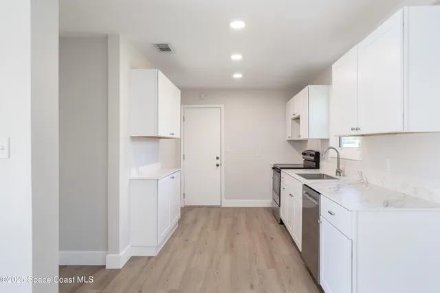 a kitchen with white cabinets appliances and sink