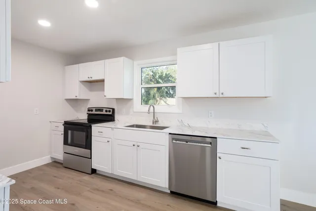 a kitchen with white cabinets sink and appliances