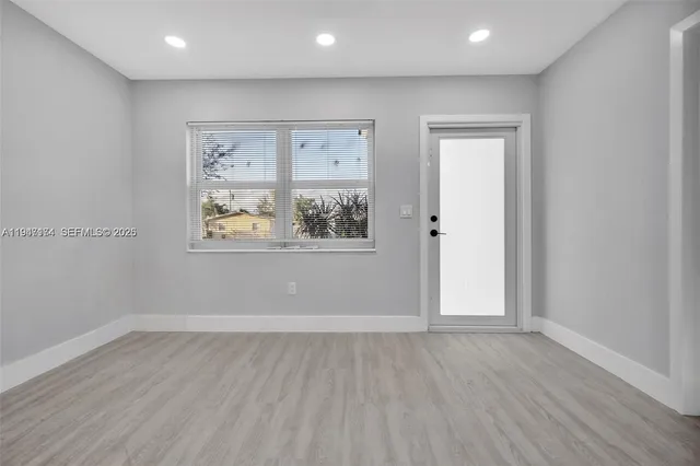 an empty room with wooden floor and window