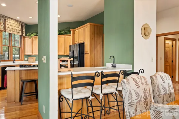 a kitchen with stainless steel appliances granite countertop a stove a refrigerator a kitchen island furniture a large window and a sink