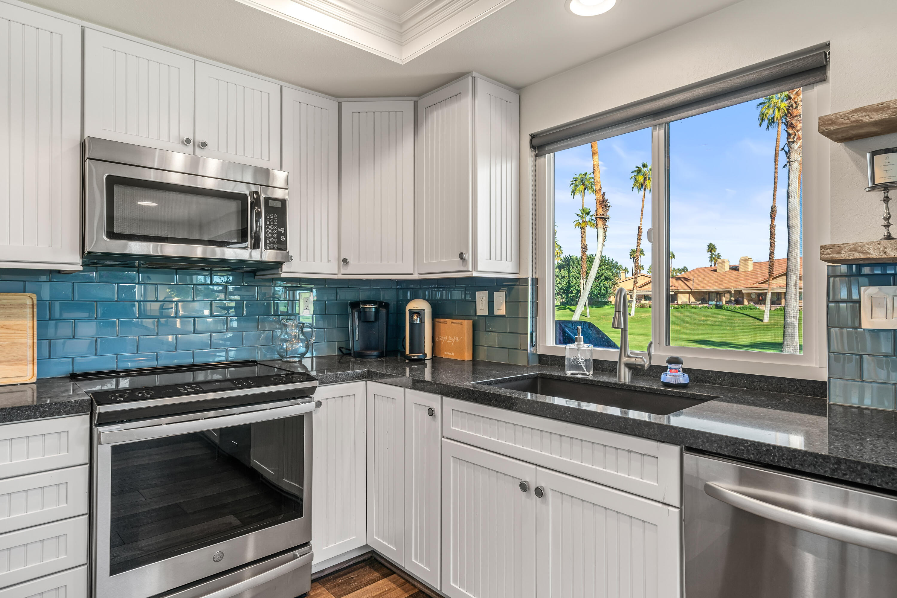 82 Conejo Circle Palm Desert, CA 92260 - Photo 15 of 58 a kitchen with stainless steel appliances granite countertop a sink a stove a microwave and cabinets