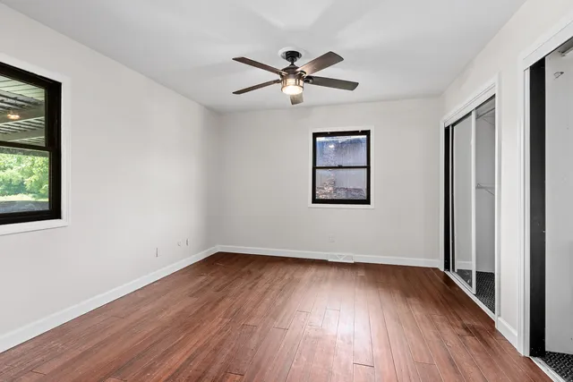 a view of empty room with wooden floor and fan